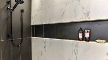 ​​​​​​​A long, walk-in shower stall allows for an gray, black