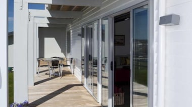 View of white exterior and wooden deck - door, floor, window, gray, white