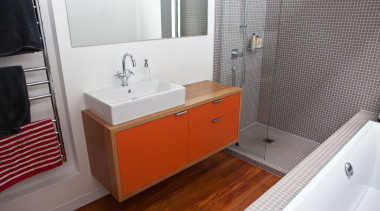Orange lacquered cabinet fronts bring a punch of bathroom, bathroom accessory, bathroom cabinet, floor, home, room, sink, tile, gray