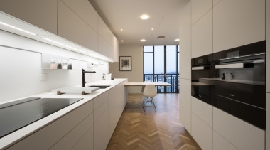 A herringbone wood floor perfectly complements the white apartment, architecture, cabinetry, countertop, cuisine classique, daylighting, floor, interior design, kitchen, property, real estate, room, gray
