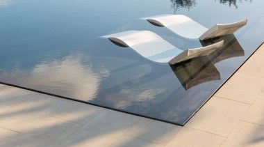 The pool seems to blend into the surrounding floor, furniture, outdoor furniture, product design, sunlounger, table, water, gray, orange