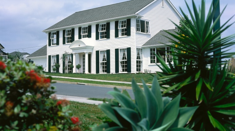 A photograph of a two storey house with building, cottage, estate, home, house, plant, property, real estate, villa, teal