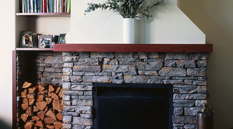 A fireplace with a stone surround. The area fireplace, hearth, wood burning stove, black, gray