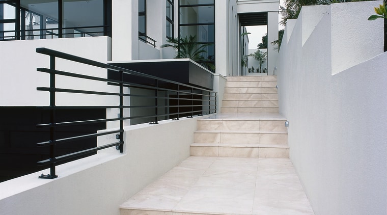 A stairway featuring coffee-coloured limestone tiles. The stairway apartment, architecture, handrail, home, house, stairs, gray