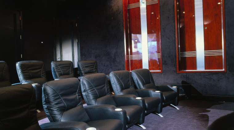 black leather coaches, dark blue carpet, wooden wall interior design, black