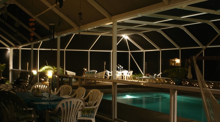 Eating area and pool area enclosed in glass lighting, night, black