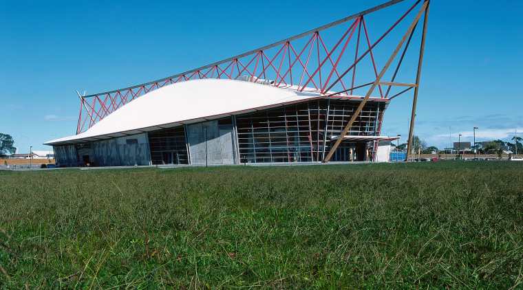 A view of a large boat shaped building, architecture, field, grass, roof, rural area, shed, sky, structure, blue, green