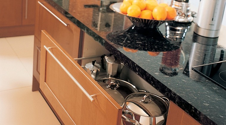 A view of a kitchen, wooden cabinetry, white cabinetry, countertop, cuisine classique, drawer, floor, flooring, furniture, hardwood, home appliance, interior design, kitchen, kitchen appliance, kitchen stove, room, tile, brown, orange, white