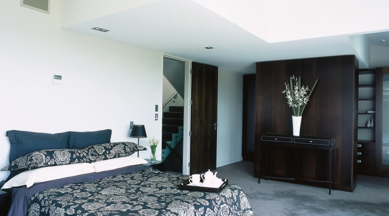 A view of a bedroom, grey carpet, white architecture, bed frame, bedroom, ceiling, floor, flooring, interior design, property, real estate, room, suite, white