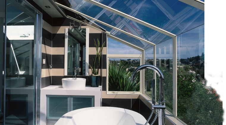 A view of a bathroom, white bathtub and architecture, daylighting, deck, glass, roof, window, black