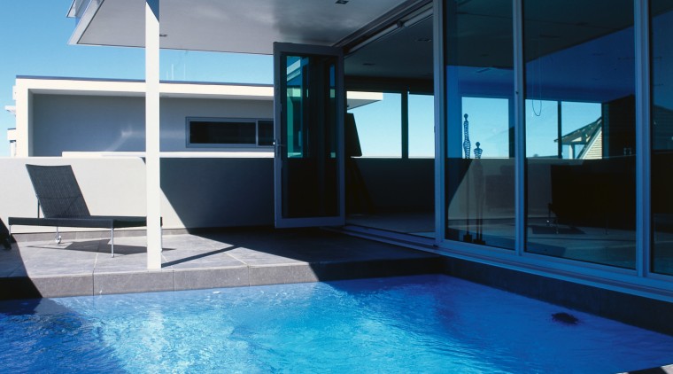 A view of a swimming pool by Pool architecture, condominium, daylighting, estate, home, house, leisure, leisure centre, lighting, property, real estate, reflection, sky, swimming pool, water, window, teal, blue