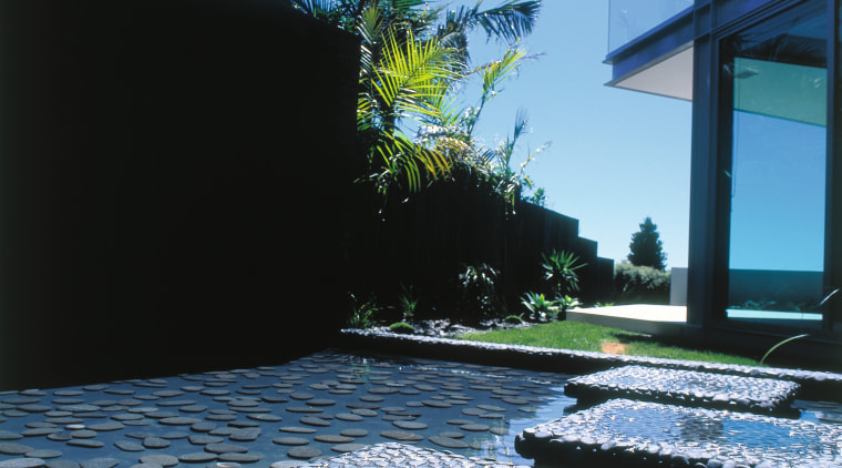 view of this rock pool featuring stepping stones, architecture, house, plant, reflection, sea, sky, tree, water, teal, black