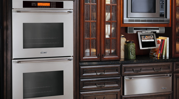View of traditional style kitchen with dark wood cabinetry, countertop, furniture, home appliance, kitchen, kitchen appliance, kitchen stove, major appliance, microwave oven, oven, refrigerator, black, gray