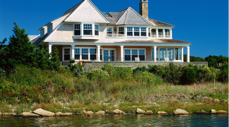 view of this cape cod home situated on building, cottage, estate, facade, home, house, lake, mansion, property, real estate, reflection, sea, sky, tree, water, waterway, blue