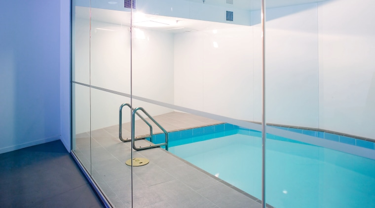 A view of a swimming pool featuring a architecture, bathroom, ceiling, floor, flooring, glass, interior design, leisure centre, lighting, room, tile, wall, white, teal