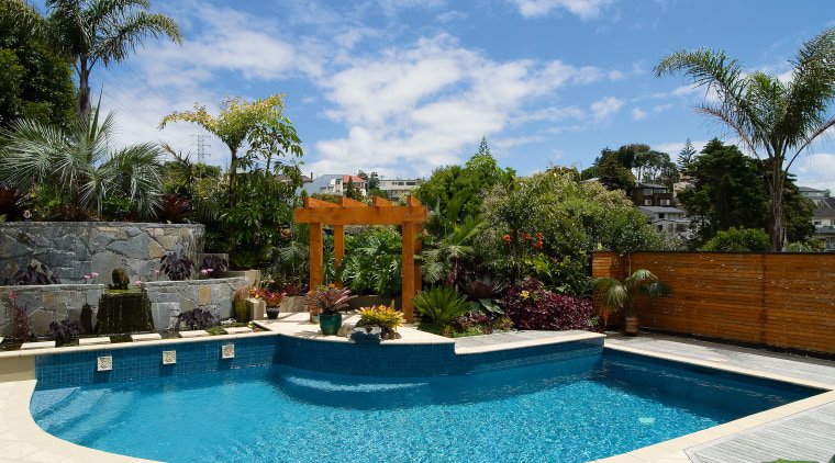 A view of this pool designed and installed arecales, backyard, estate, home, landscaping, leisure, outdoor structure, palm tree, property, real estate, resort, swimming pool, tree, villa, water feature, teal