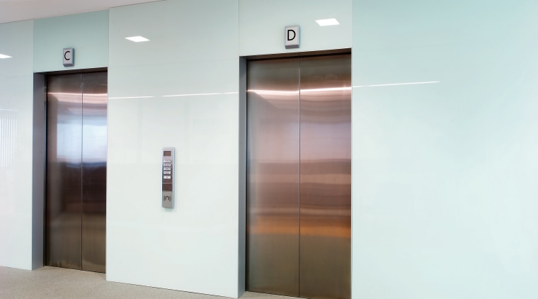 A view of the elevator lobby feauting glass door, elevator, glass, white