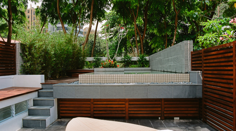 A view of this outdoor entertainment area featuring backyard, courtyard, estate, furniture, house, landscaping, outdoor furniture, outdoor structure, patio, plant, property, real estate, table, walkway, wall, yard