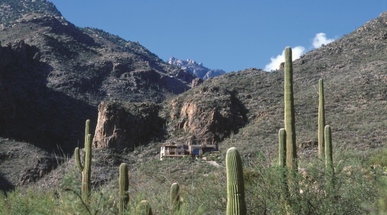 An exterior view of this Tuscan desert home, escarpment, fell, geological phenomenon, highland, mount scenery, mountain, mountain pass, mountain range, mountainous landforms, plant community, ridge, shrubland, sky, tree, valley, wilderness, gray, teal