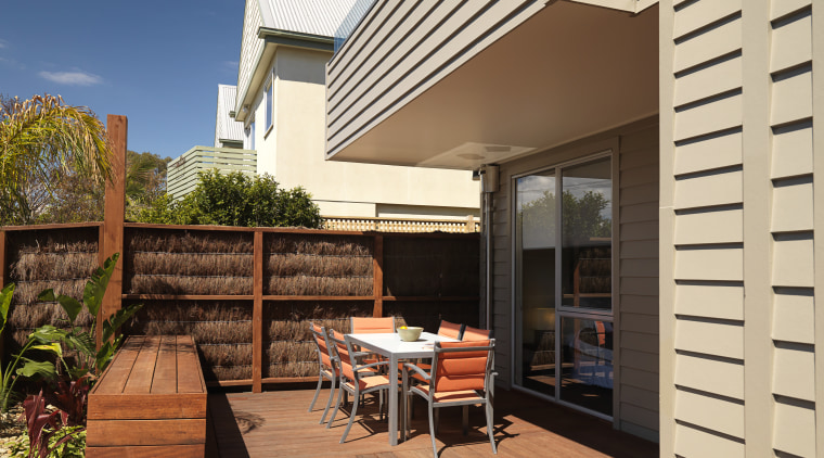 An exterior of this house featuring Merbau decking, deck, home, house, outdoor structure, real estate, residential area, siding, orange