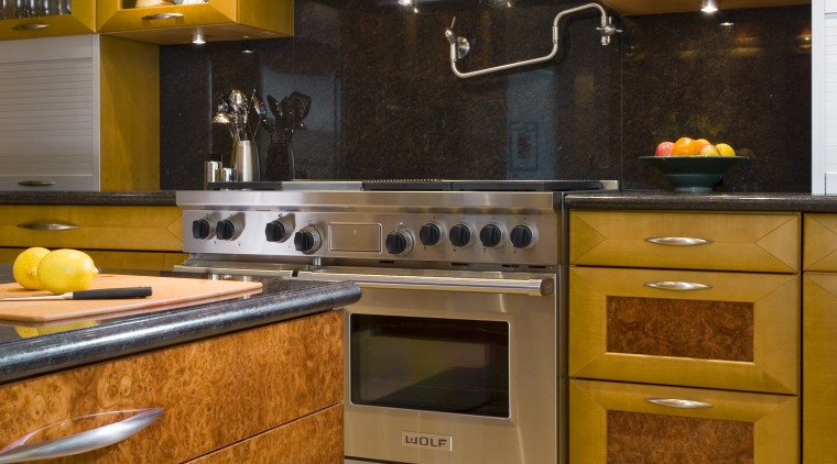 view of kitchen featuring cooking appliances, cooktop, oven, cabinetry, countertop, cuisine classique, floor, flooring, hardwood, interior design, kitchen, kitchen stove, room, under cabinet lighting, wood flooring, brown, orange