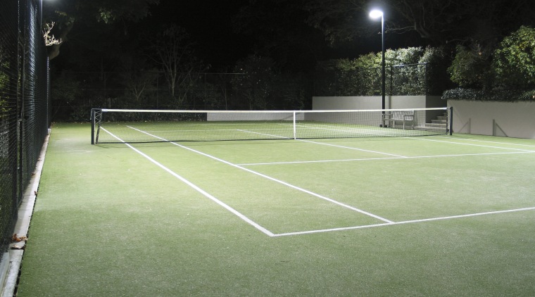 Image of a residential tennis court which was artificial turf, ball game, grass, net, plant, racquet sport, real tennis, sport venue, sports, structure, tennis, tennis court, green, black
