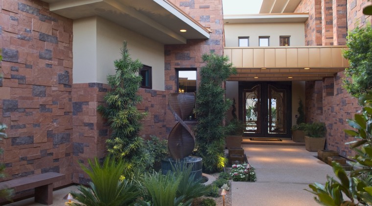 The sheltered, welcoming entry provides a glimpse of backyard, courtyard, estate, facade, garden, home, house, landscaping, outdoor structure, property, real estate, residential area, window, yard, gray