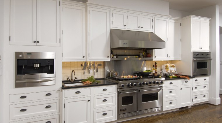 View of kitchen with white painted maple cabinetry, cabinetry, countertop, cuisine classique, floor, flooring, home appliance, kitchen, kitchen appliance, kitchen stove, room, gray