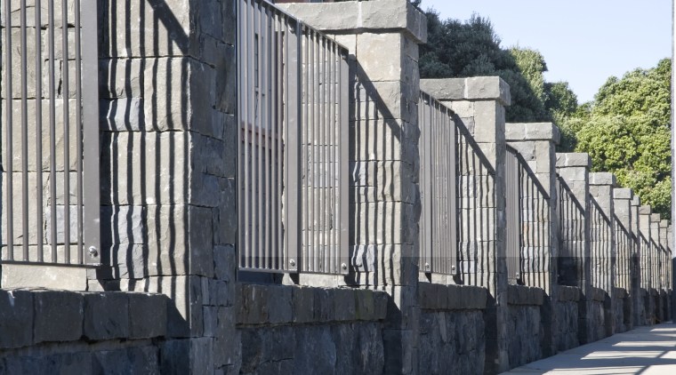 View of the stone wall with metal sections architecture, building, facade, fence, guard rail, handrail, home fencing, house, infrastructure, iron, lane, neighbourhood, outdoor structure, residential area, road, structure, walkway, wall