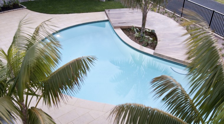 View of a resort-styled pool which was built arecales, backyard, estate, house, leisure, palm tree, plant, property, real estate, reflection, resort, swimming pool, vacation, water, gray