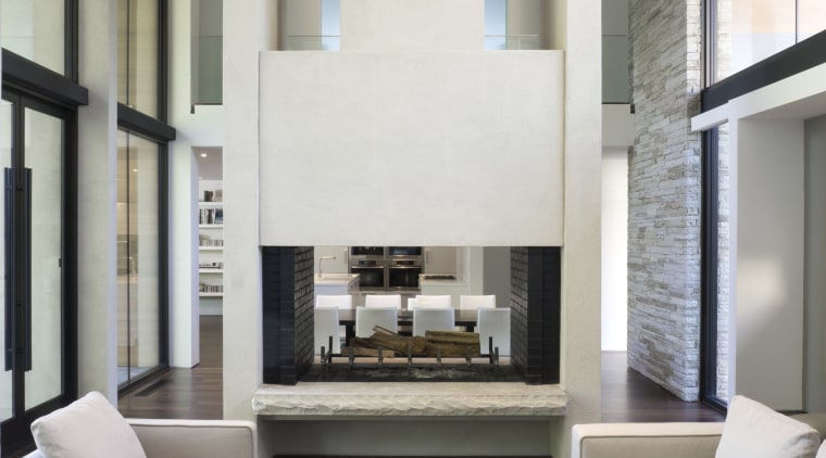 View of living area featuring double story fireplace, architecture, ceiling, floor, furniture, house, interior design, living room, table, white, gray