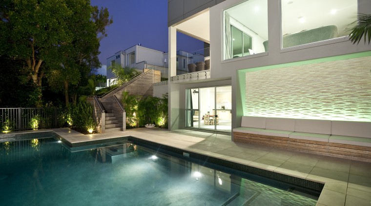 View of sleek poolscape with textured stone wall, apartment, architecture, condominium, estate, home, house, interior design, lighting, property, real estate, residential area, swimming pool, villa, window