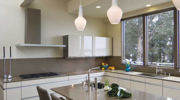View of neutral-toned kitchen and dining space, featuring architecture, ceiling, countertop, daylighting, floor, house, interior design, kitchen, real estate, table, gray