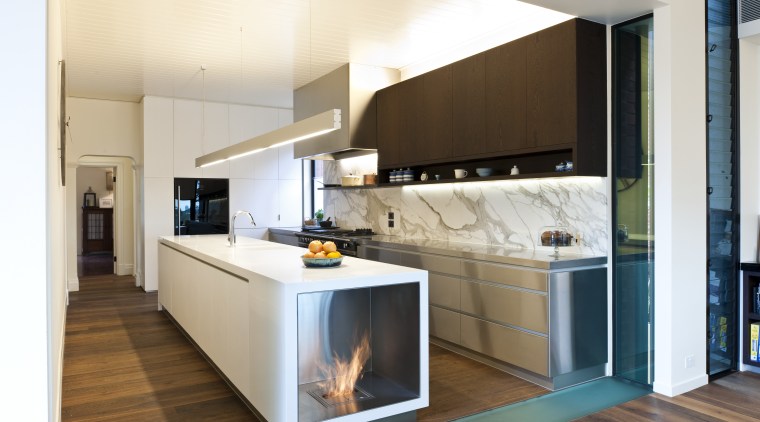 Fireplace built into island. Stainless steel appliances. Minimalistic cabinetry, countertop, cuisine classique, home appliance, interior design, kitchen, room, white