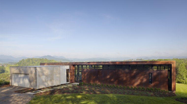 Exterior of house with rusted corten steel. Sustainable architecture, cloud, estate, grass, home, horizon, house, land lot, landscape, property, real estate, rural area, sky, sunlight, teal