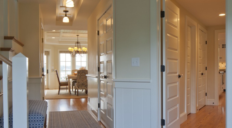 In this Cape Cod house, corridors lead off apartment, architecture, ceiling, daylighting, door, estate, floor, flooring, hardwood, home, house, interior design, laminate flooring, living room, lobby, real estate, room, wall, window, wood, wood flooring, gray, brown