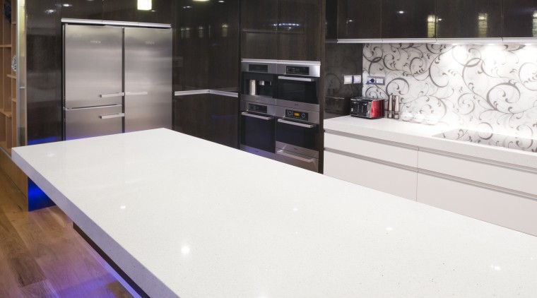 The 60mm-thick composite stone benchtop in this kitchen ceiling, countertop, floor, flooring, glass, interior design, kitchen, lighting, room, table, white