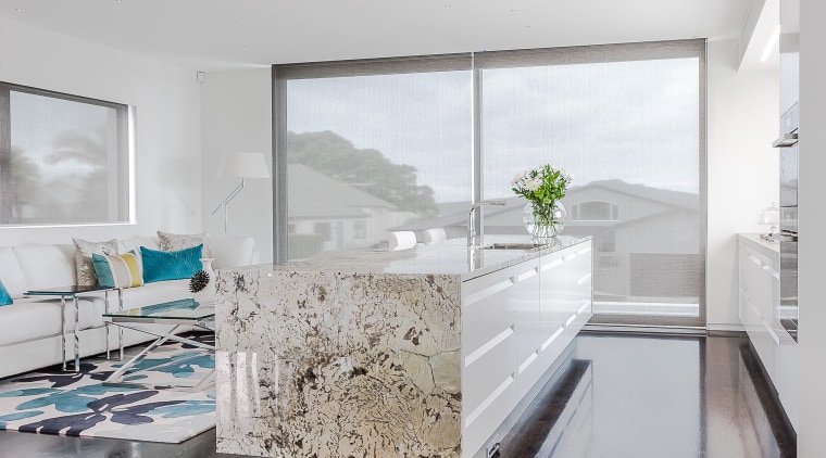 A textural granite benchtop with waterfall ends wraps apartment, architecture, ceiling, daylighting, floor, flooring, hardwood, home, house, interior design, laminate flooring, living room, wood, wood flooring, gray