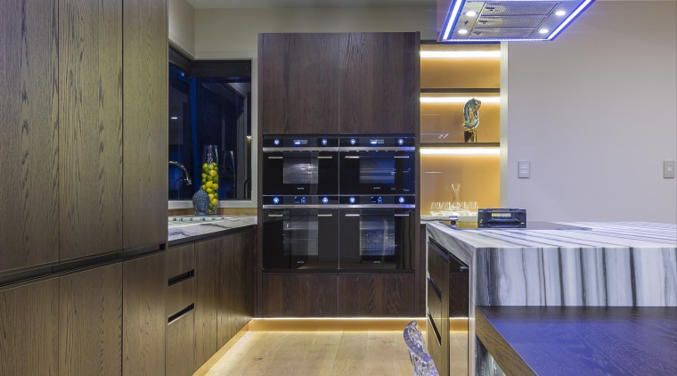 A bank of four black Smeg ovens is apartment, architecture, ceiling, countertop, floor, flooring, hardwood, house, interior design, kitchen, real estate, room, wood, wood flooring, gray