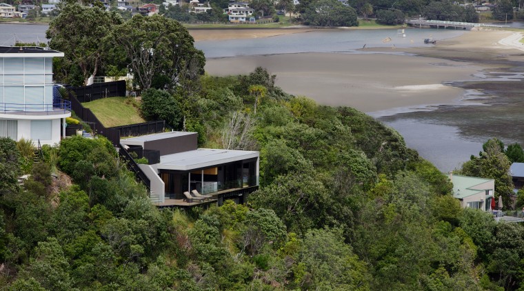 Hidden from the street above, the holiday home home, house, property, real estate, residential area, suburb, tree, water, brown, gray