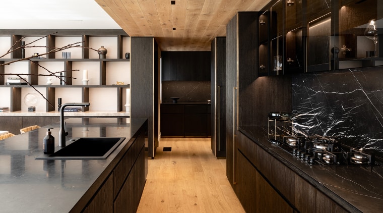 The dark-toned kitchen cabinetry finds a material echo 