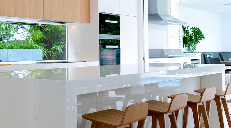 An extended waterfall countertop provides breakfasters with leg architecture, bar stool, building, cabinetry, ceiling, countertop, dining room, floor, flooring, furniture, hardwood, home, house, interior design, kitchen, material property, property, real estate, room, stool, table, white, gray