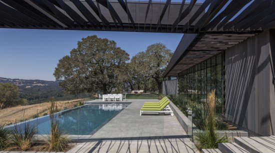 While the trellis running alongside the two wings architecture, estate, home, house, landscape, outdoor structure, plant, property, real estate, roof, sky, black