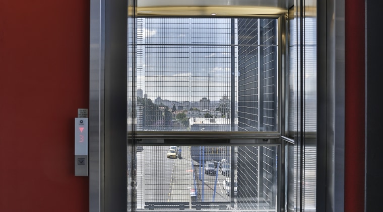 An external elevator with a stainless steel and architecture, door, facade, glass, window, red, gray