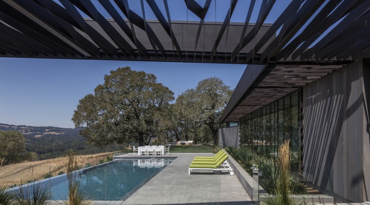 While the trellis running alongside the two wings architecture, estate, home, house, landscape, outdoor structure, plant, property, real estate, roof, sky, black