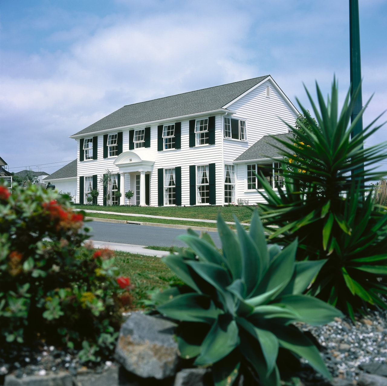 A photograph of a two storey house with building, cottage, estate, home, house, plant, property, real estate, villa, teal