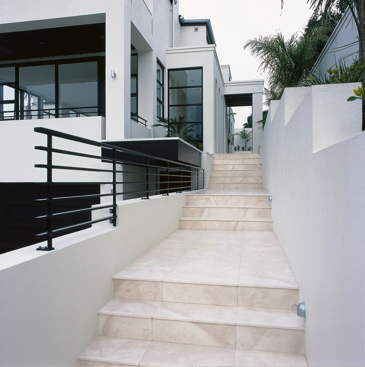 A stairway featuring coffee-coloured limestone tiles. The stairway apartment, architecture, handrail, home, house, stairs, gray