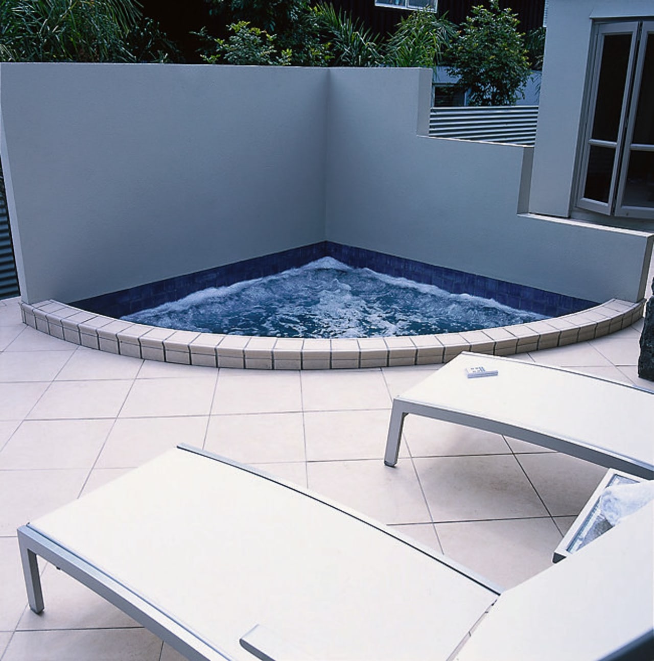 A small cornered spa pool. The area also angle, chair, daylighting, floor, furniture, glass, outdoor furniture, product, sunlounger, swimming pool, table, white, blue