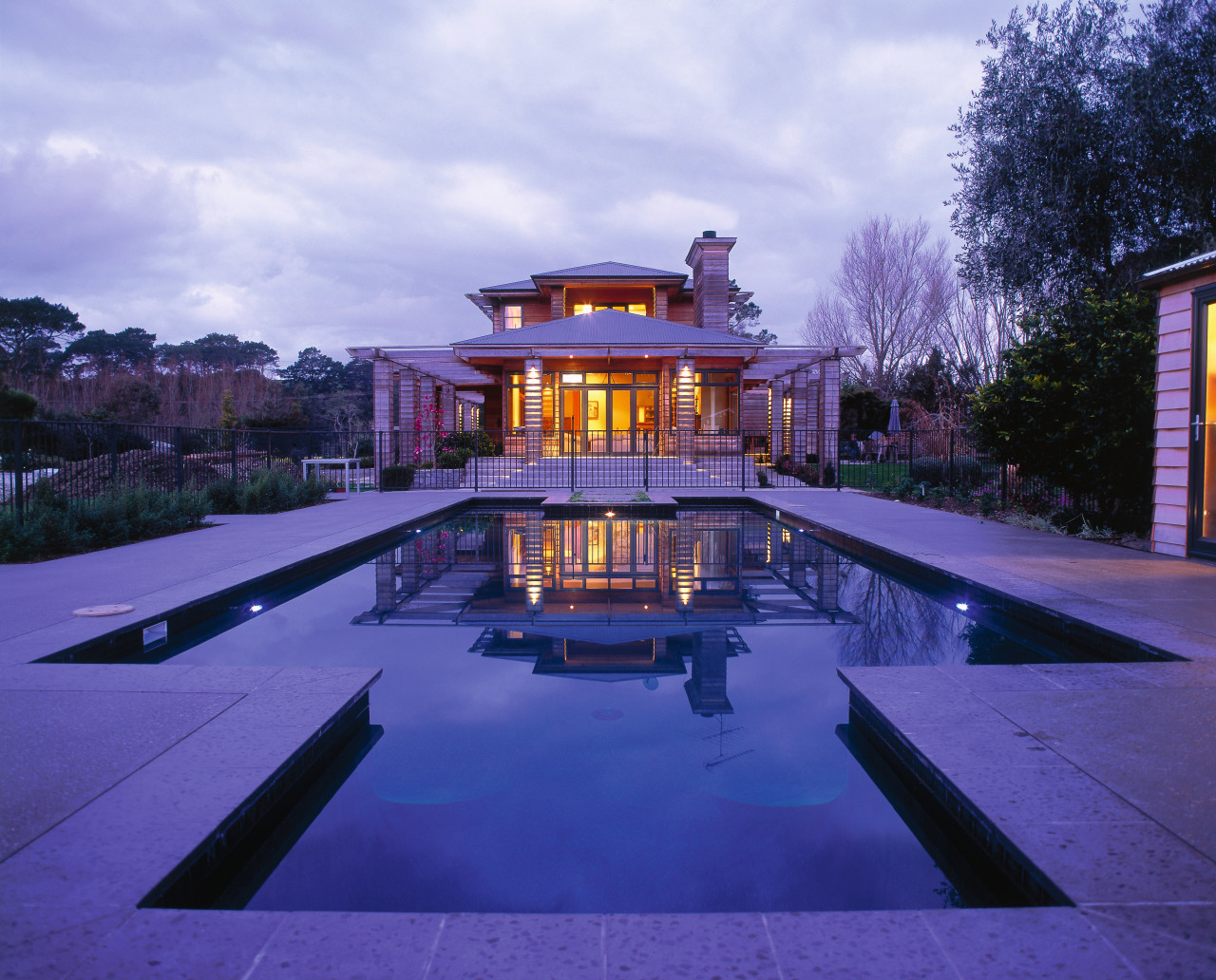 View of the pool in front of two architecture, estate, evening, home, house, lighting, mansion, property, real estate, reflection, residential area, sky, swimming pool, villa, blue