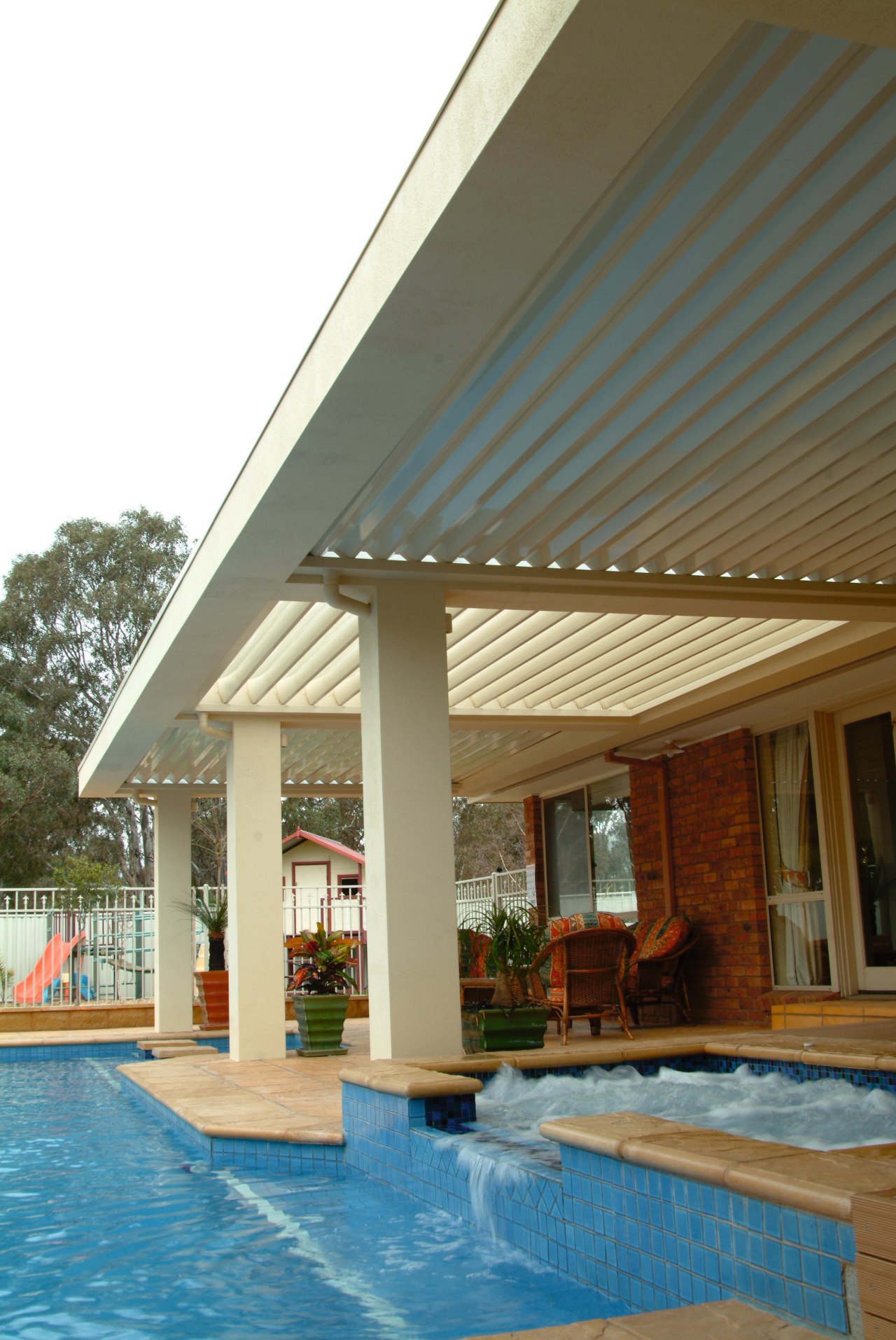 Outdoor living space showing vergola and water feature awning, daylighting, outdoor structure, property, real estate, roof, shade, swimming pool, brown